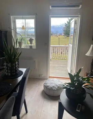 a living room with a table and chairs and a sliding glass door at Ingeborgstova in Lii