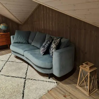 a blue couch in a room with a wooden wall at Mountain Cabin With Sauna In Sunnmørsalpane in Brunstad