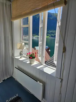 a room with a window with a view of the water at Sentralt i Sogndal terrasse med fjordutsikt in Sogndal