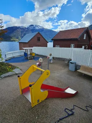 two children playing in a playground with a slide at Sentralt i Sogndal terrasse med fjordutsikt in Sogndal