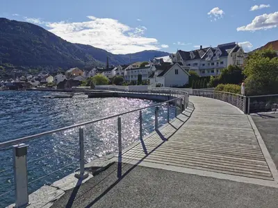 a wooden boardwalk next to a body of water at Sentralt i Sogndal terrasse med fjordutsikt in Sogndal