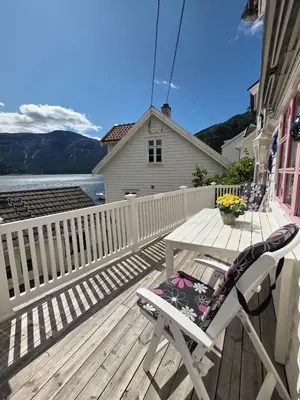 a wooden deck with a table and a chair on it at Sentralt i Sogndal terrasse med fjordutsikt in Sogndal