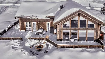 a house covered in snow with a porch at Modern Family Cabin By The Ski Lift in Flå