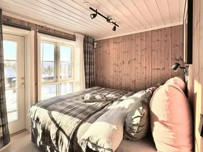 a bedroom with a bed in a room with wooden walls at Modern Family Cabin By The Ski Lift in Flå