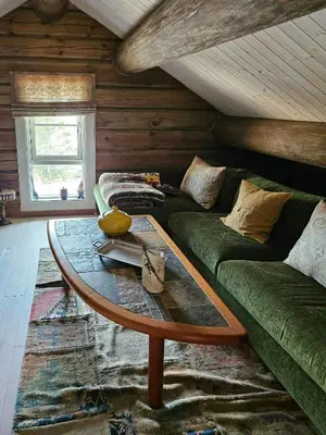 a living room with a green couch and a table at Timber Cabin With Mountain Views In Synnfjellet in Skartlia