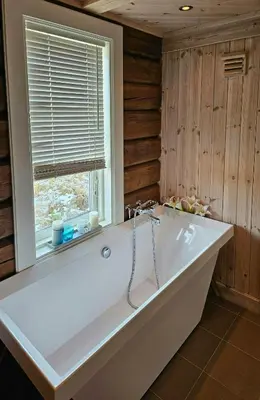 a large white tub in a room with a window at Timber Cabin With Mountain Views In Synnfjellet in Skartlia