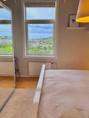 a bedroom with a bed and two windows at Stor 3-roms leilighet med utsikt in Trondheim