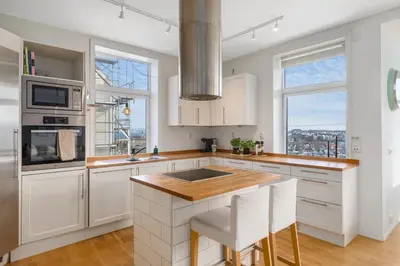 a kitchen with white cabinets and a large window at Stor 3-roms leilighet med utsikt in Trondheim