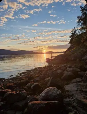 a sunset on the shore of a body of water at Summer villa with heated pool 50 min from Bergen