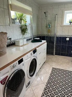 a washing machine in a bathroom with a shower at Summer villa with heated pool 50 min from Bergen