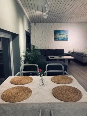 a table with four chairs and a living room at Petersstova in Ålesund