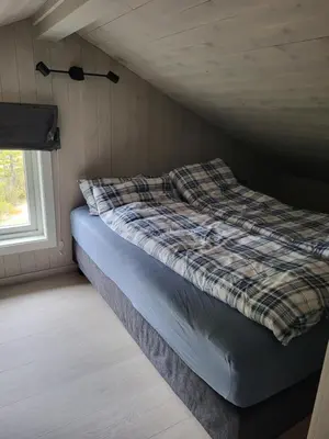 a bed sitting in a room with a window at Koselig liten fjellhytte i flott turterreng både sommer og vinter in Hovda