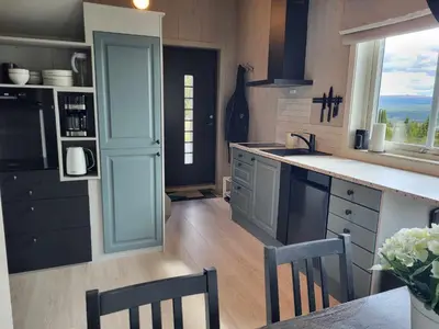 a kitchen with blue cabinets and a table and chairs at Koselig liten fjellhytte i flott turterreng både sommer og vinter in Hovda