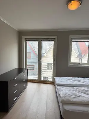 a bedroom with two beds and a dresser and windows at Modern Apartment in City Center with Parking Garage in Ålesund