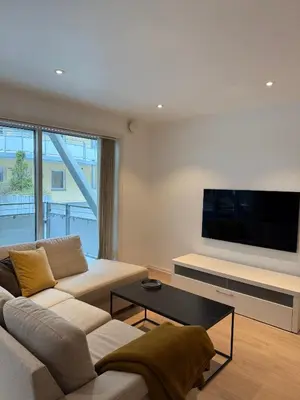 a living room with a couch and a flat screen tv at Modern Apartment in City Center with Parking Garage in Ålesund