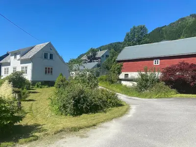 a red barn and a white house next to a road at Cozy house closw in Lii