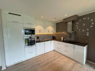 a kitchen with white cabinets and a clock on the wall at Loen Panorama View in Loen
