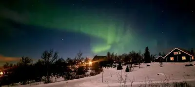 an aurora in the sky above a house in the snow at Lauvåsen - Langleiken in Sør-Fron