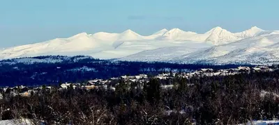 a snowy mountain range with houses and trees in front at Lauvåsen - Langleiken in Sør-Fron