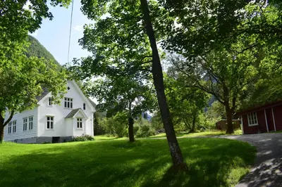 a white house on a green lawn with trees at Large house by nature reserve