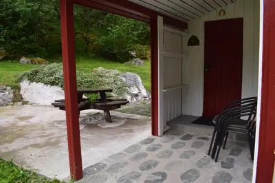 a porch with a picnic table and a bench at Skogshytte in Bjordal