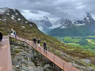 a group of people walking on a bridge over a mountain at Bakkebo in Åndalsnes