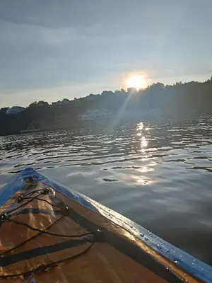 a kayak on the water with the sun in the background at Koselig hus med egen brygge in Askøy