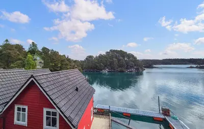 a red house on the shore of a lake at Cozy Home In Lepsøy With House Sea View in Lepsøy