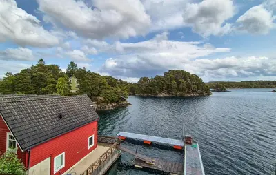 a red house on a dock next to a body of water at Cozy Home In Lepsøy With House Sea View in Lepsøy