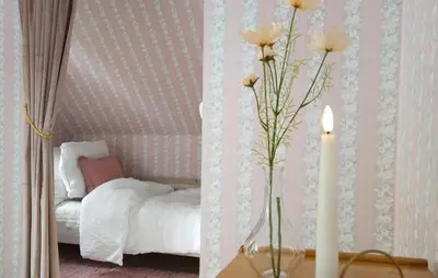 a vase with flowers on a table next to a bed at Awesome Home In Fitjar With Wifi in Fitjar