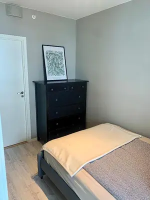 a bedroom with a bed and a dresser with a picture at Lys og moderne 3-roms på Sandsli in Bergen
