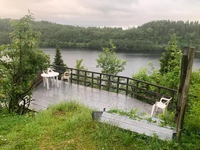 a table and chairs on a boardwalk next to a lake at Cabin at Hestsjøen Badeplass in Trondheim