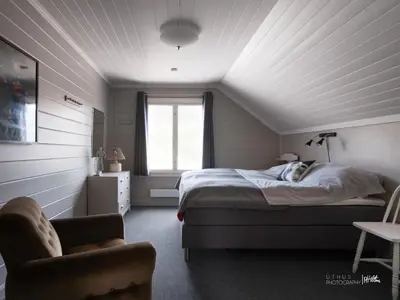 a bedroom with a bed and a chair and a window at Hus nær butikk, sentrum & rekreasjon in Hol