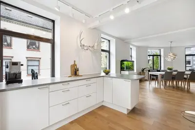 a kitchen with white cabinets and a dining room at A Gem in the Heart of Ålesund in Ålesund