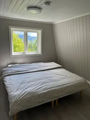 a bed in a room with a window at Vestlandsidyll ved sjøen & Bergen