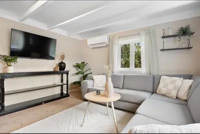a living room with a gray couch and a tv at Vestlandsidyll ved sjøen & Bergen