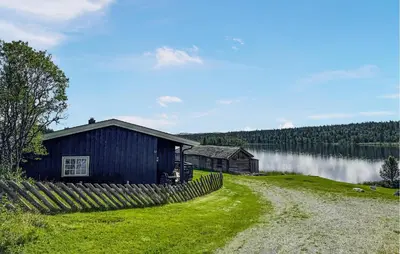 a blue barn and a fence next to a lake at 2 Bedroom Lovely Home In Nesbyen in Nesbyen