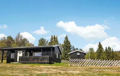 a black cabin with a deck on a field at 2 Bedroom Lovely Home In Nesbyen in Nesbyen