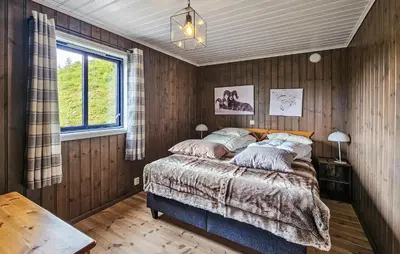 a bedroom with a bed with wooden walls and a window at Stunning Home In Edland With Sauna in Nesland