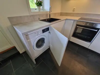 a kitchen with a washing machine and a sink at Cozy flat with lake view and 15 min from Bergen in Bergen