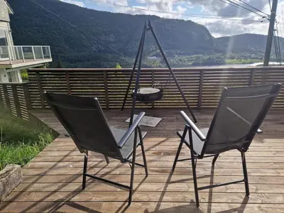 two chairs sitting on a deck with a swing at Cozy flat with lake view and 15 min from Bergen in Bergen