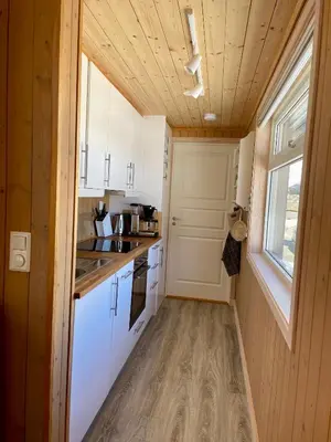 a small kitchen with white cabinets and a window at Hytte sentralt i Myrkdalen in Vossevangen