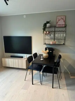a living room with a table with chairs and a flat screen tv at Apartment Lademoen Trondheim in Trondheim