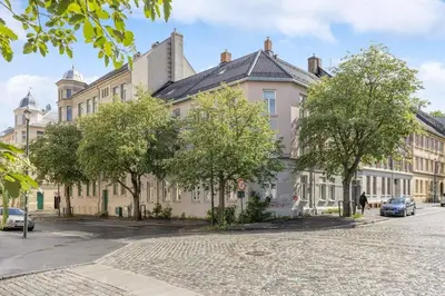 a large building with trees in front of a street at Apartment Lademoen Trondheim in Trondheim
