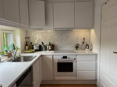 a kitchen with white cabinets and a sink and a stove at The house next to the fjord in Trondheim