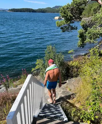 a man walking down stairs next to a body of water at Gorgeous views and sunsets in Halsnøy, Kvinnherad in Ådnavik
