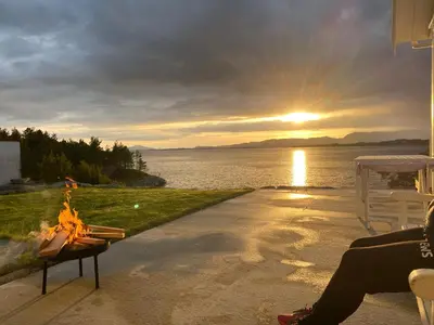 a woman sitting on a porch watching the sunset at Gorgeous views and sunsets in Halsnøy, Kvinnherad in Ådnavik
