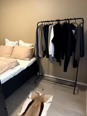 a bedroom with a bed and a rack of clothes at Modern central apartment in a quiet area in Bergen