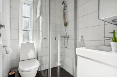 a white bathroom with a toilet and a sink at Bright apartment with mountain views in Bergen