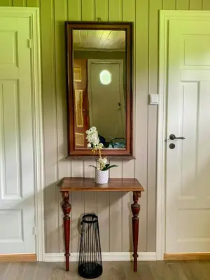 a mirror and a table with flowers on it at Historic Log House At The Foot Of Middagstind in Sæbø